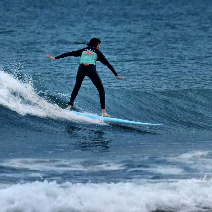 Un surfeur en train de prendre une vague bleu sur une plage d'Anglet