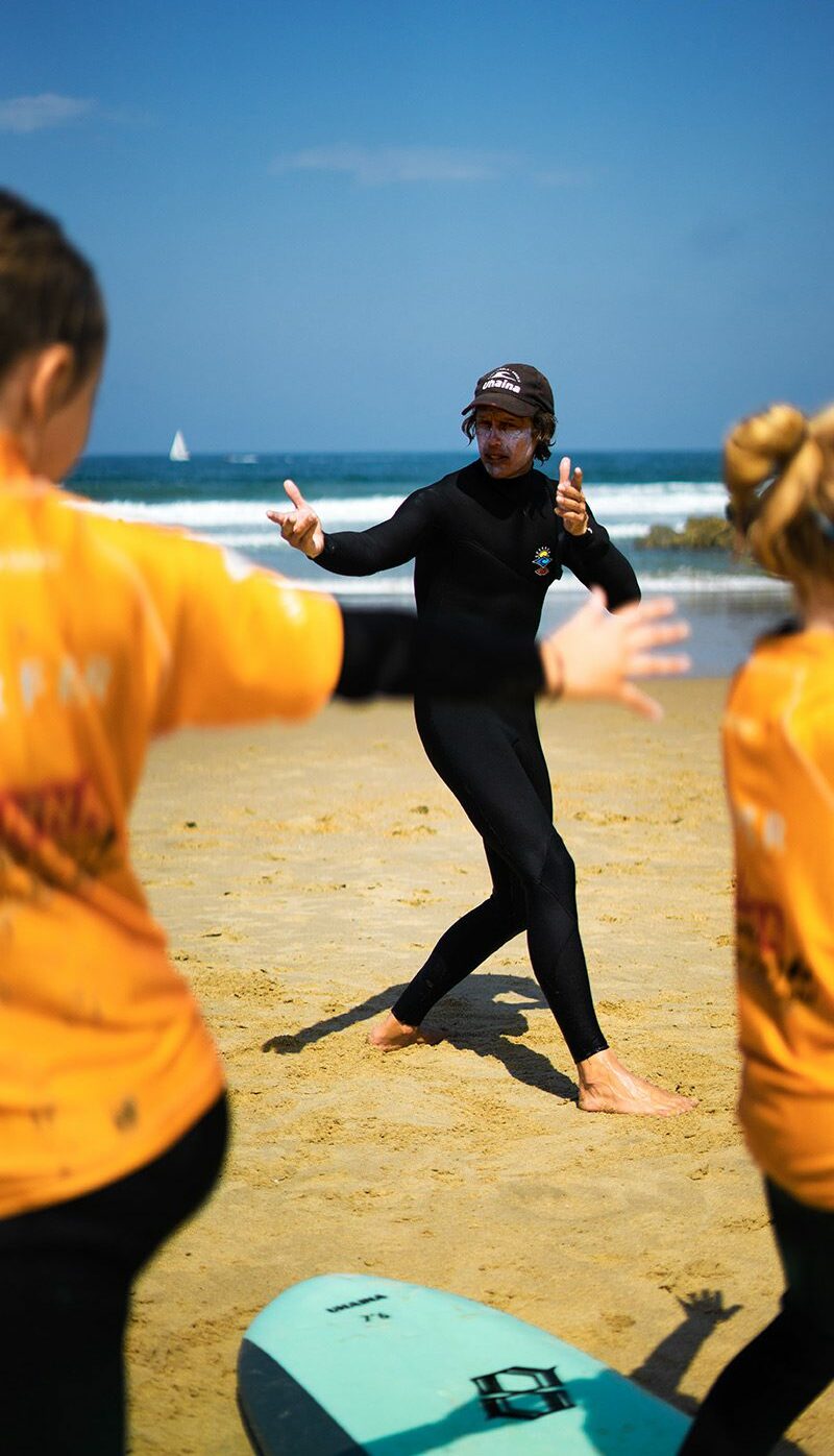 Moniteur de surf expliquant les mouvements d'échauffement à un groupe sur la plage d'Anglet
